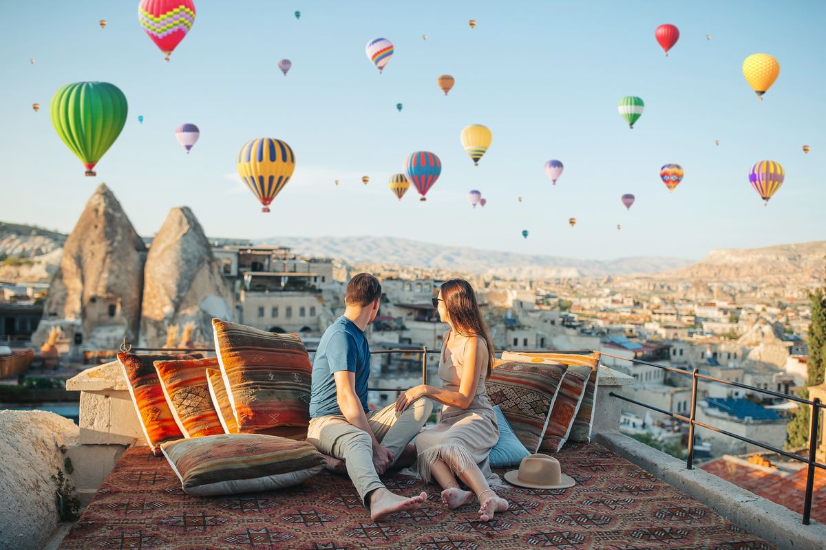 Casal em um terraço na Capadócia vendo os balões ao nascer do sol